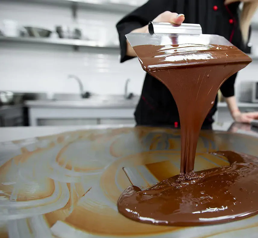 Tempered dark chocolate being worked on a marble surface