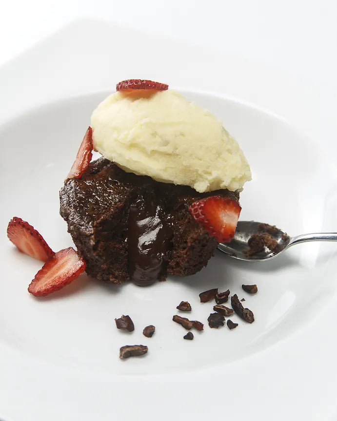 Chocolate fondant with a molten center, plated with red fruit