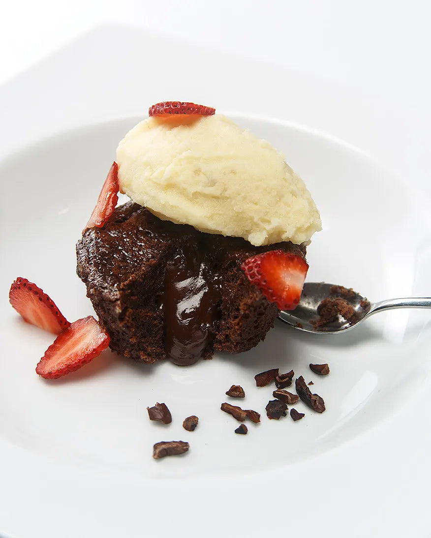 Un fondant de chocolate emplatado con helado y fruta fresca